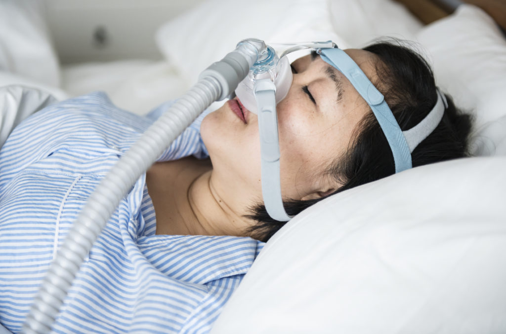 Mulher dorme tranquilamente enquanto utiliza CPAP para conter o ronco e a apneia