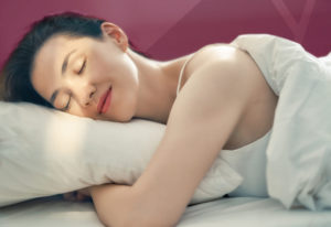 Mulher dormindo tranquilamente enquanto sorri. Uma boa noite de sono proporciona uma boa qualidade de vida, o que é o objetivo da Odontologia do Sono